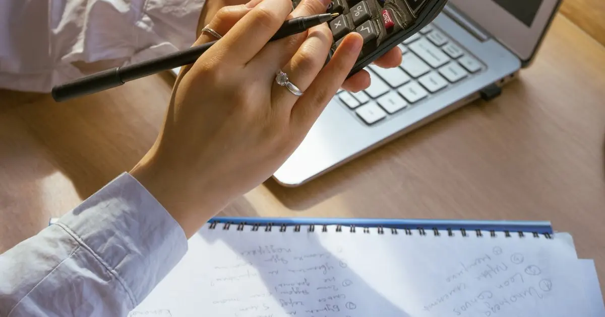 Bàn làm việc với máy tính xách tay, máy tính bấm và sổ ghi chép khi tính chi phí làm website